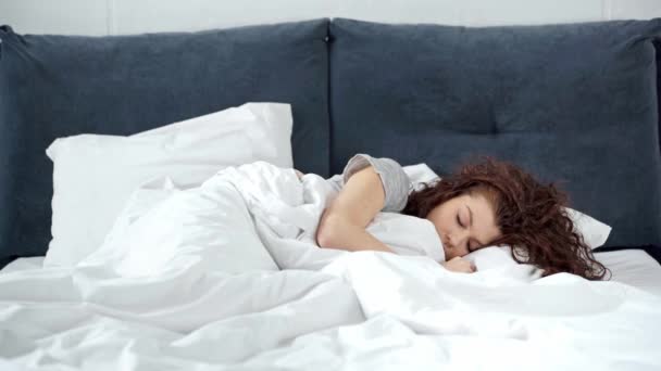 Красива Дівчина Спить Ліжку Прокидається Розтягується Дивиться Камеру Вранці — стокове відео
