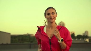 gülme ile çatıda çalışan spor giyim büyüleyici sporcu, kameraya bakarak