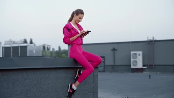 Mooie Sportvrouw Sportswear Zittend Het Dak Texting Bericht Smartphone — Stockvideo