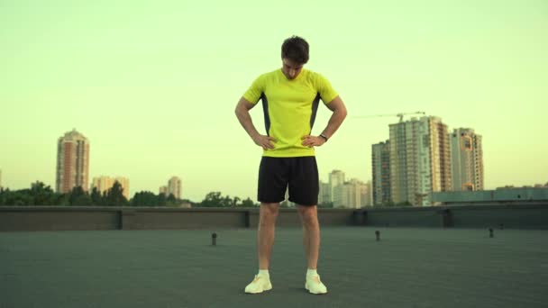 엉덩이에 옥상에 서있는 스포츠맨의 각도보기 머리를 돌리기 워밍업 스트레칭 — 비디오