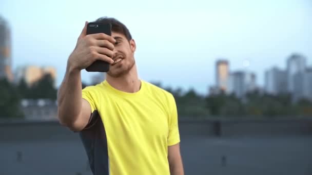 Όμορφος Αθλητής Κίτρινα Αθλητικά Είδη Κρατώντας Smartphone Στο Χέρι Μιλώντας — Αρχείο Βίντεο
