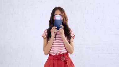 neşeli genç kadın pasaport ve uçak bileti parmak ile işaret ederken kameraya gülümseyen, başparmak gösteren, atlama, dans ve kazanan jest gösteren