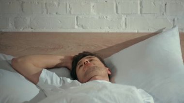 beyaz t-shirt adam yatakta uyku, uyanma ve gülümseme ile kameraya bakarak