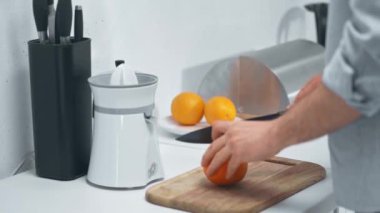 mutfakta ahşap kesme tahtası üzerinde portakal kesme adam kısmi görünümü