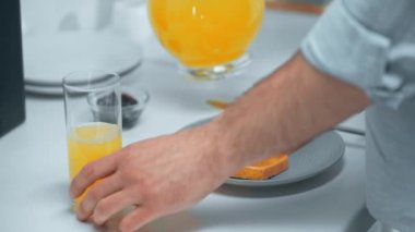 cam portakal suyu döken ve ekmek tost üzerinde reçel uygulayarak adam kırpılmış görünümü