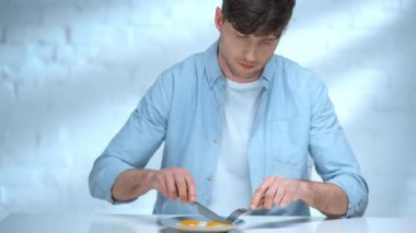 mutfakta çırpılmış yumurta yerken bıçak ve çatal kullanarak odaklanmış adam