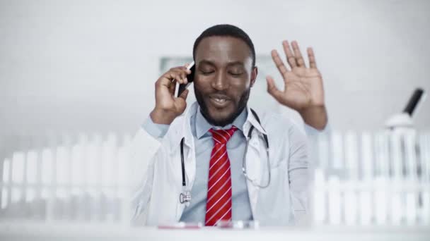 Vrolijke Afro Amerikaanse Dokter Glimlachend Gebaren Tijdens Het Praten Smartphone — Stockvideo