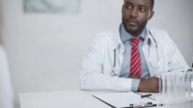 afro-amerikan doktor meslektaşı ile el sıkışma ve hastanede işyerinde otururken gülümseyerek