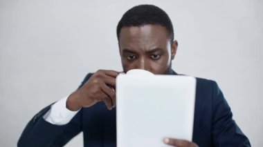 Afro-Amerikan iş adamı dijital tablet kullanıyor ve ofiste kahve içiyor.