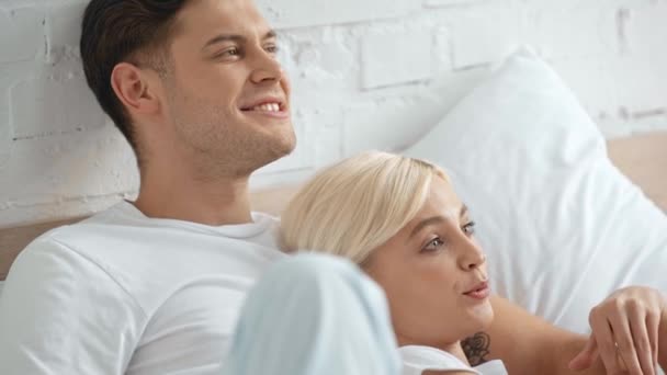 美丽的女人说话 拥抱和抚摸微笑的男人在床上喝咖啡 — 图库视频影像
