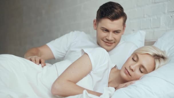 英俊的男人拥抱和醒来睡觉的女人在床上接吻 — 图库视频影像