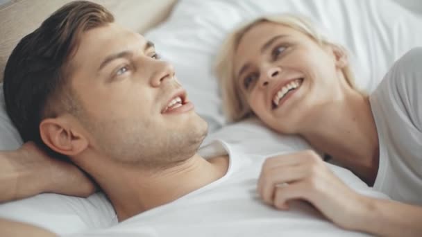 男人说话和抚摸美丽的笑和微笑的女人在床上 — 图库视频影像