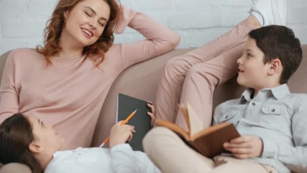 Gülümseyen Anne Ders Kitabı Ile Kızı Oturma Odasında Kanepe Üzerinde — Stok video