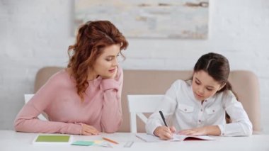 anne el ile yüz propping ve o kopya kitap yazarken pensive kızı ile konuşurken