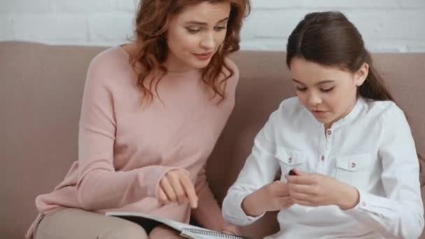 Attractive Mother Sitting Sofa Helping Daughter Homework — Stock Video