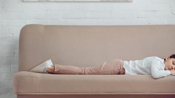疲れた十代の女子高生がソファに横たわり コピーブックと本の隣で寝ている — ストック動画