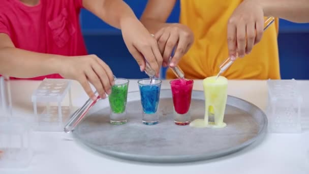 裁剪视图的孩子添加水在五颜六色的液体 — 图库视频影像