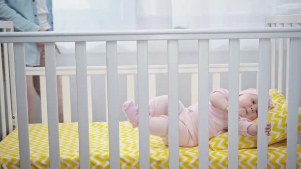 赤ちゃんのベビーベッドに横たわっている娘を取って幸せな母親 — ストック動画