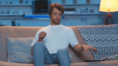 oturma odasında kanepede tv izleyen genç adam