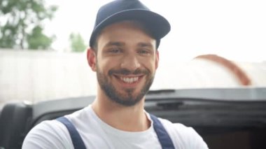 arabanın yanında çapraz kolları ile gülümseyen teslimat adam