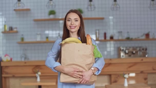 自宅で食料品と紙袋を保持する陽気な女の子 — ストック動画