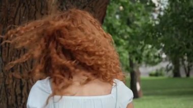 parkta gülümseyen mutlu kızıl saçlı kadının seçici odak 