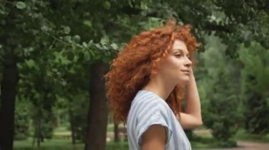 kıvırcık kızıl saçlı kadının seçici odak parkta yürüyüş 