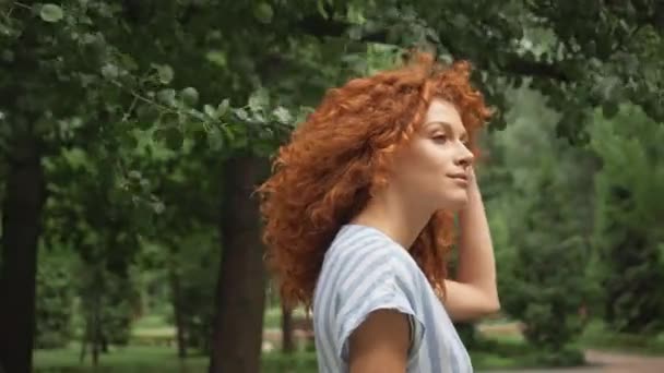 公園を歩く巻き毛の赤毛の女性の選択的な焦点 — ストック動画