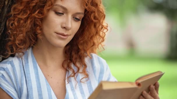 公園で本を読むカーリー女性の選択的な焦点 — ストック動画