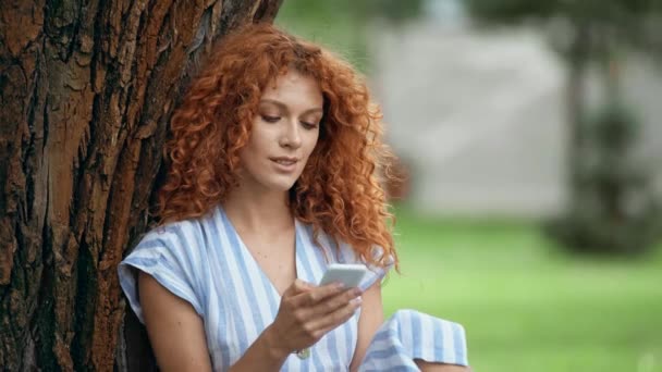 Verrast Redhead Meisje Met Behulp Van Smartphone Park — Stockvideo