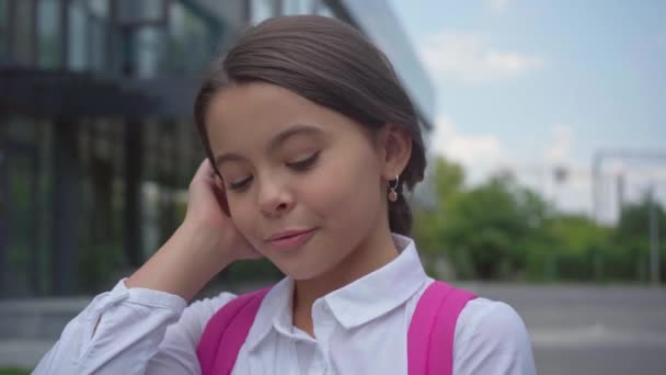 校庭でバックパックを持つ幸せな恥ずかしがり屋の女子高生 — ストック動画