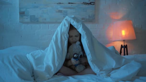 害怕的孩子晚上坐在毯子下在床上 — 图库视频影像