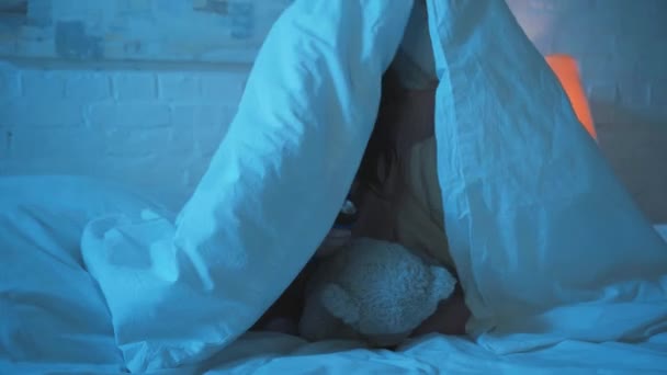 害怕的孩子晚上坐在毯子下用手电筒 — 图库视频影像
