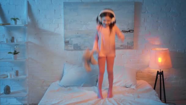 Bambino Cuffia Che Salta Sul Letto Notte — Video Stock