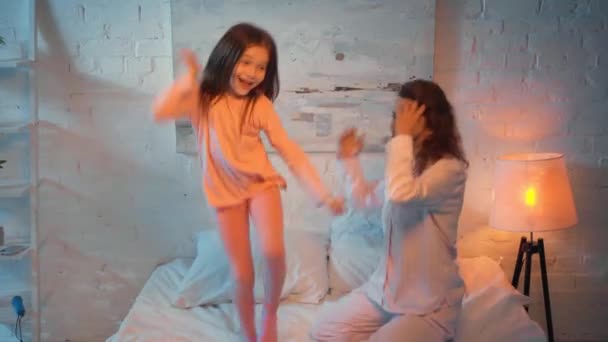 母亲和女儿晚上在床上跳 — 图库视频影像
