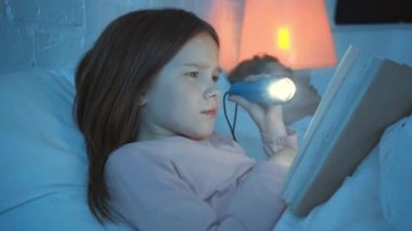 uyuyan anne yakınında el feneri ile kızı kitap okuma