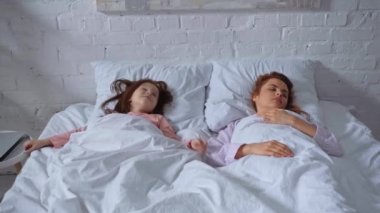 anne sabah uyurken kızı uyanma ve dizüstü bilgisayar kullanarak