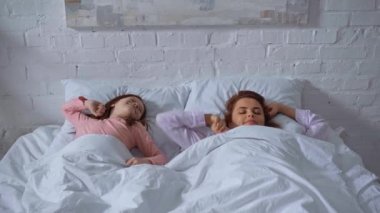 mutlu anne ve kızı uyanma ve yatakta el ele tutuşarak