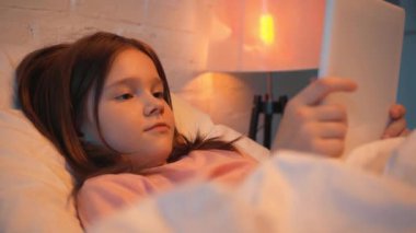 gece yatakta dijital tablet kullanan çocuk