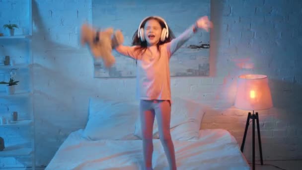 Збуджена Дитина Навушниках Танцює Ліжку Вночі — стокове відео
