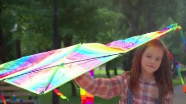 parkta gökkuşağı uçurtma ile yürüyen sevimli çocuk