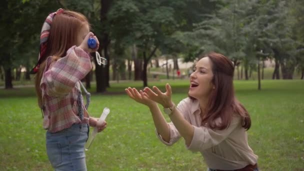 緑の公園で石鹸の泡を吹く母と娘 — ストック動画