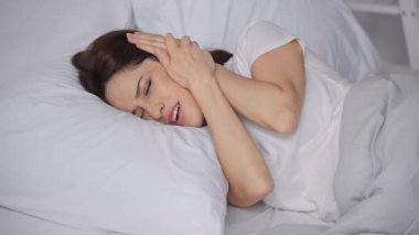 kadın yatakta yatan ve gürültü muzdarip