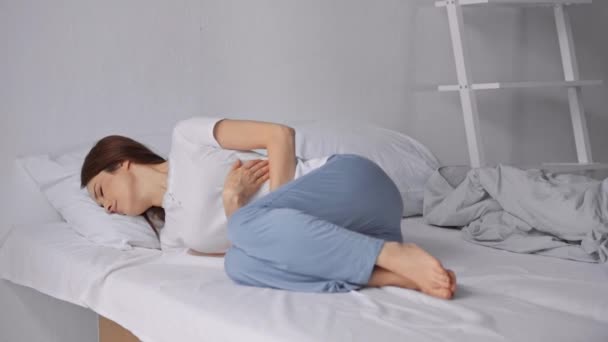 ベッドに横たわり 胃の痛みに苦しむ女性 — ストック動画