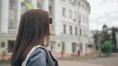 binalar ile cadde boyunca yürüyen genç kadın