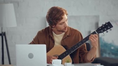 dizüstü ekranbakarken akustik gitar çalan redhead adam