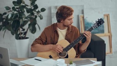 akustik gitar çalan ve müzik kitabında yazan besteci