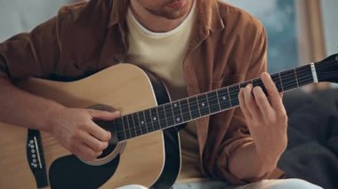 kanepede akustik gitar çalan adamın kırpılmış görünümü