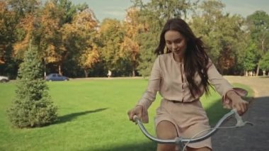 Parkta bisiklet süren genç bir kadın.