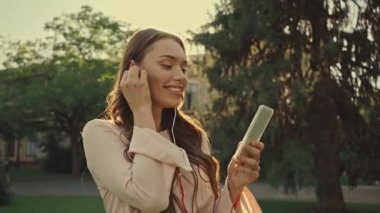 parkta akıllı telefonda müzik dinleyen genç kadın